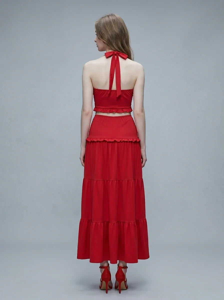 Woman wearing a red halter crop top and a tiered maxi skirt, back view