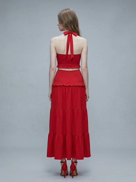 Woman wearing a red halter crop top and a tiered maxi skirt, back view