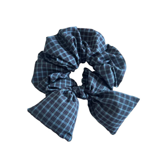 Oversized scrunchie with a dark blue and black plaid pattern and a matching bow detail.