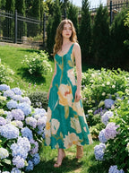 Woman standing in a garden surrounded by hydrangeas wearing a teal floral print midi dress