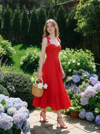 Woman wearing a red midi dress with tie straps and ruffle hem, holding a basket in a garden.