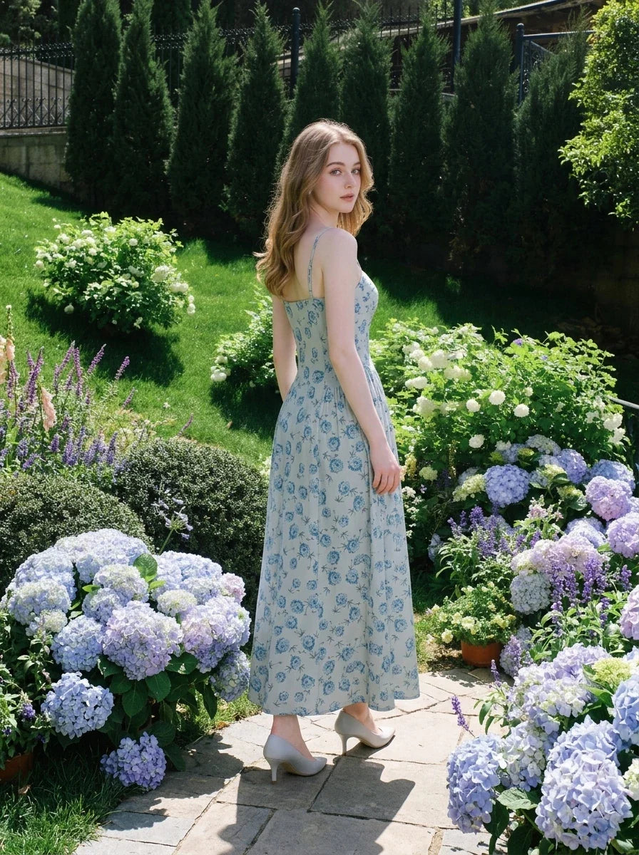 Woman in a floral print midi dress with hydrangea bushes in the background.