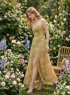 woman in a green floral strapless maxi dress with a high slit posing in a rose garden