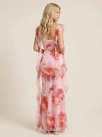 Back view of a woman in a pink floral print maxi dress with ruffle trim