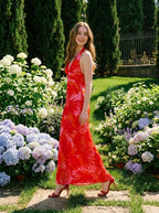 Woman in a red and pink tropical print halter maxi dress walking in a garden