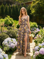 Woman walking in a garden wearing a floral print maxi dress with a high slit and carrying a straw bag