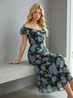 Woman sitting on a bench wearing a black off-the-shoulder midi dress with a blue floral print