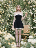 woman in black and white off-the-shoulder dress holding round object in rose garden