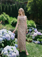 Woman wearing a strapless, patterned maxi dress posing in a garden with hydrangeas.