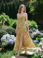 woman in a green floral strapless maxi dress with a high slit standing in a garden with hydrangeas