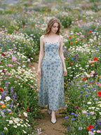 Woman walking through a field of wildflowers wearing a floral print midi dress.
