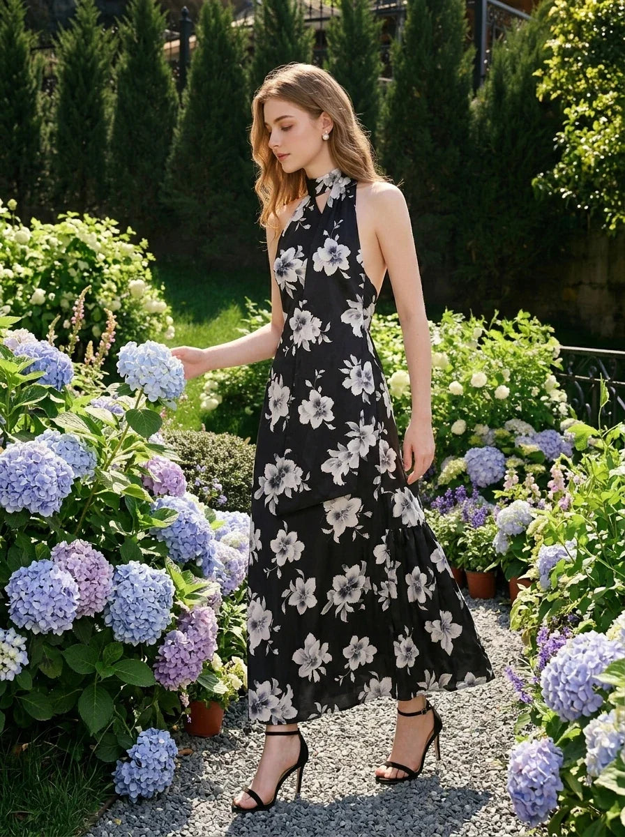 woman wearing a black floral maxi dress with a halter neck walking through a garden