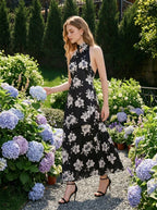 woman wearing a black floral maxi dress with a halter neck walking through a garden