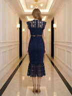 Back view of a woman in a navy blue lace mermaid dress with a high neck and cap sleeves.