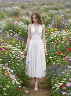 Woman in a white halter neck midi dress walking through a field of colorful wildflowers.