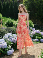 Woman walking in a garden wearing a strapless floral print midi dress with a side slit.