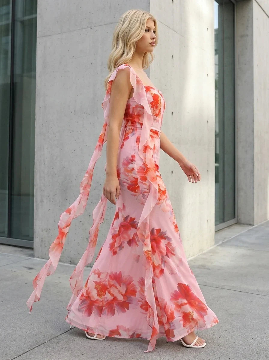 Woman walking in a pink floral print maxi dress with ruffle trim outdoors