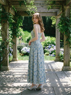 Woman in a floral print midi dress posing in a garden setting.