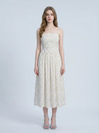 Woman wearing a white floral print midi dress with spaghetti straps and a square neckline, standing against a white background.