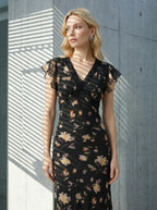 Close-up of a woman wearing a black floral print midi dress with lace trim.