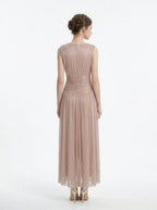 Woman in a rose gold shimmering metallic A-line V-neck sleeveless floor-length formal gown, back view