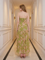 back view of a woman in a green floral strapless maxi dress with a high slit