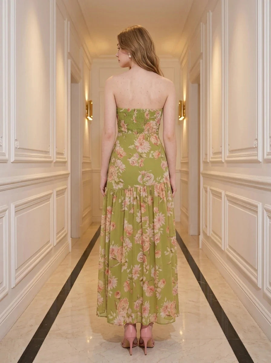 back view of a woman in a green floral strapless maxi dress with a high slit