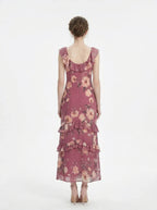 Woman wearing a pink floral print maxi dress with ruffle trim, back view