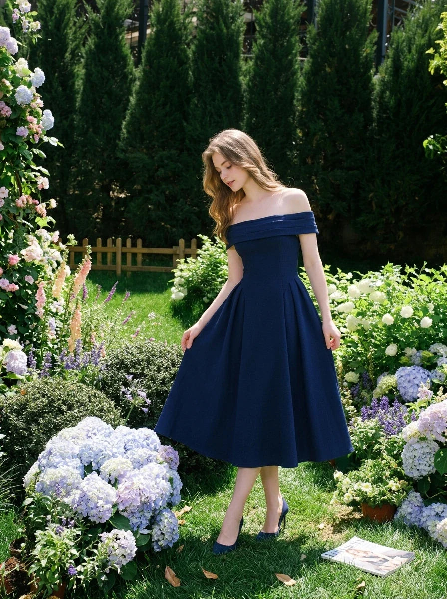 Woman wearing a navy blue off-the-shoulder midi dress with a pleated skirt, posing in a garden with hydrangeas.