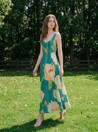 Woman walking in a grassy field wearing a teal floral print midi dress