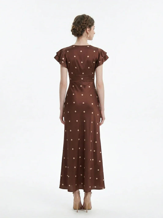 Back view of a woman wearing a brown polka dot midi dress with ruffled sleeves and a v-neckline, standing against a white background.