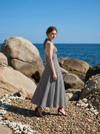Woman wearing a black and white gingham halter maxi dress posing on a rocky beach