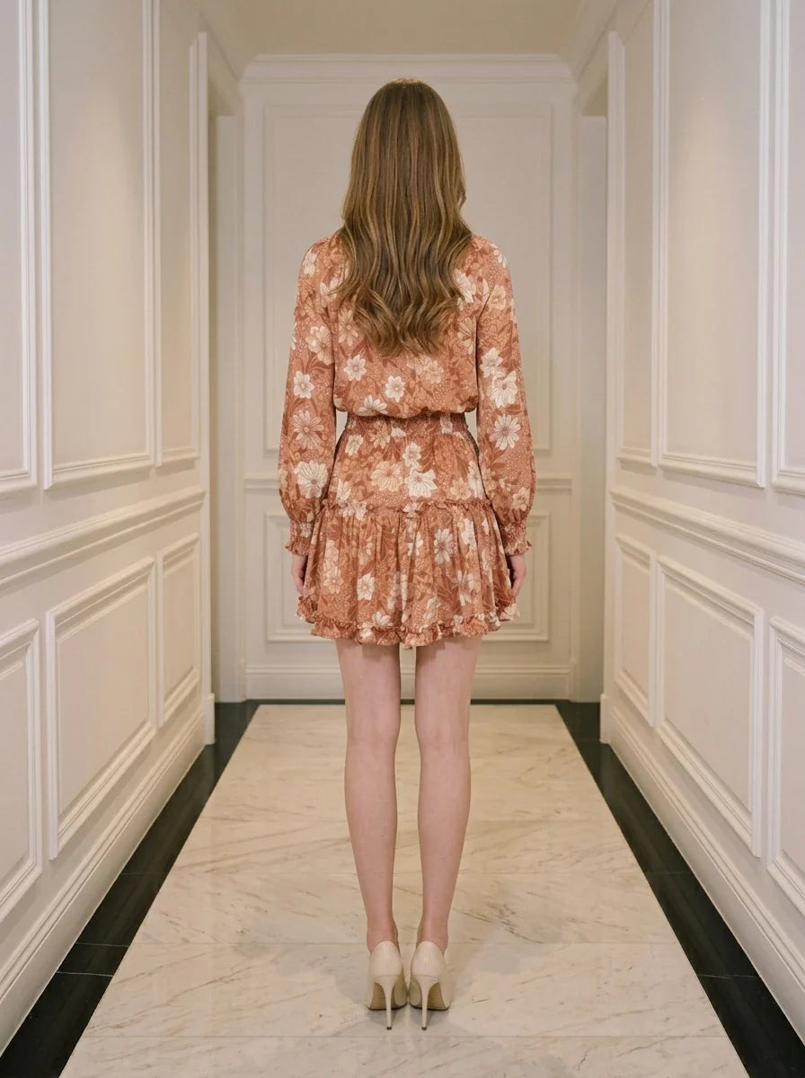 Back view of a woman wearing a floral print mini dress with long sleeves and a V-neck.
