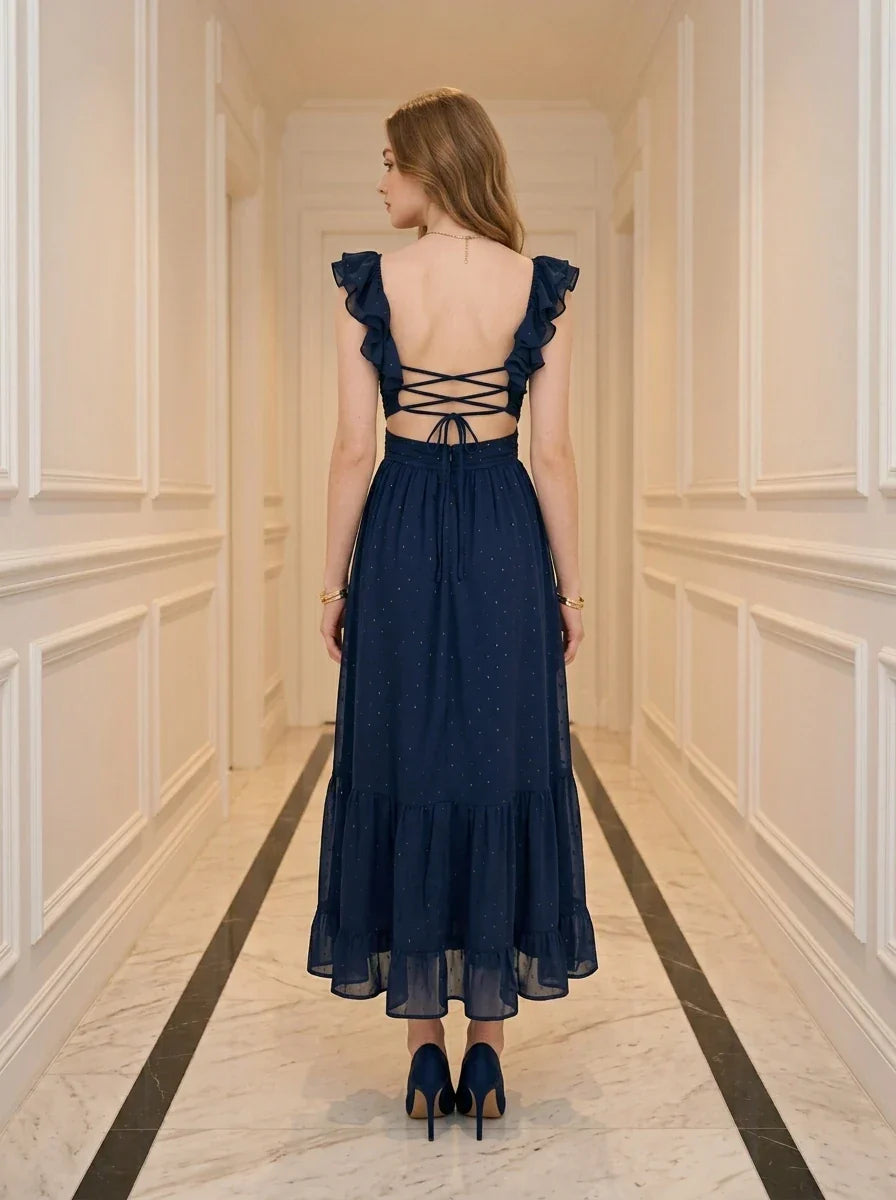 Back view of a woman in a navy blue midi dress with a criss-cross back detail and tiered ruffled hem.
