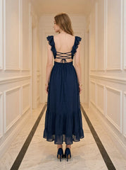 Back view of a woman in a navy blue midi dress with a criss-cross back detail and tiered ruffled hem.
