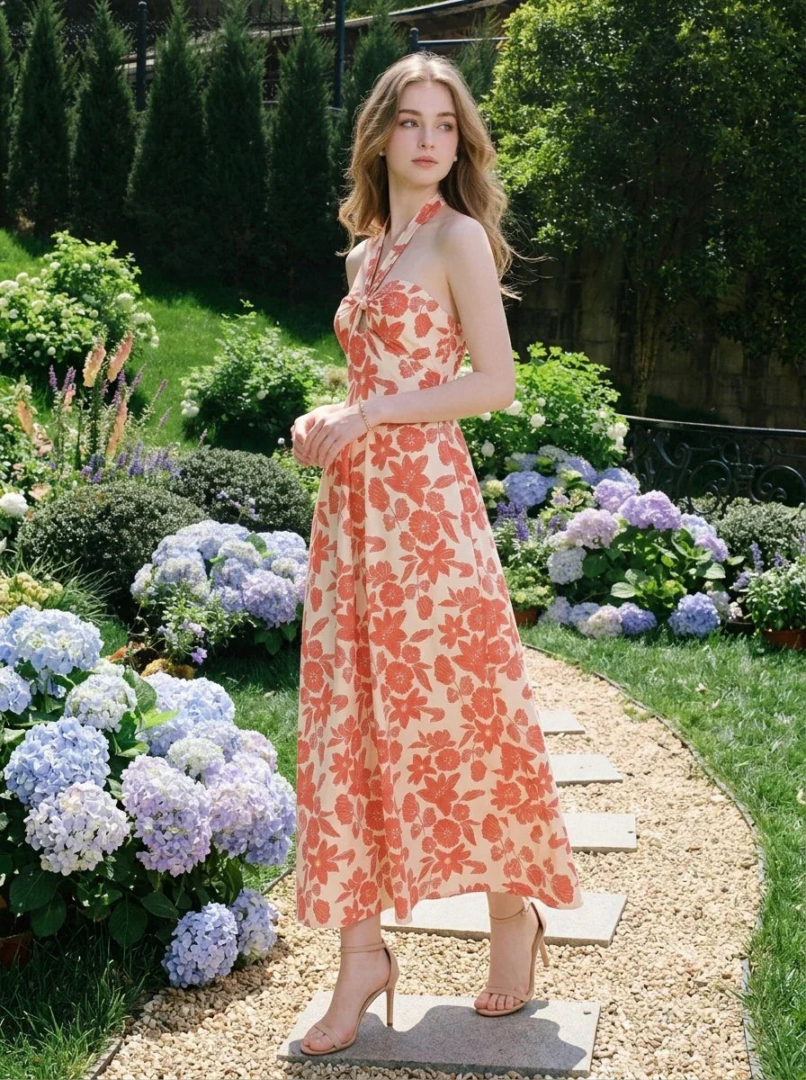Woman wearing a cream and coral floral print halter midi dress, standing in a garden with hydrangeas.