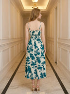 Back view of a woman wearing a floral print midi dress with spaghetti straps and a smocked back, standing in a hallway.