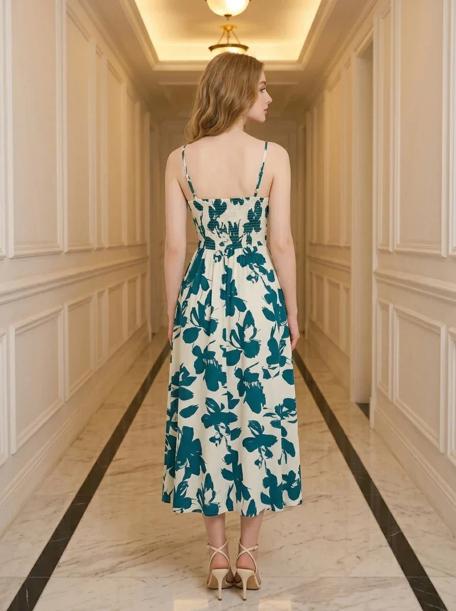 Back view of a woman wearing a floral print midi dress with spaghetti straps and a smocked back, standing in a hallway.