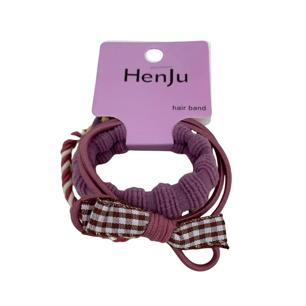 Close-up of a lavender hair tie with a brown and white plaid bow. Main image
