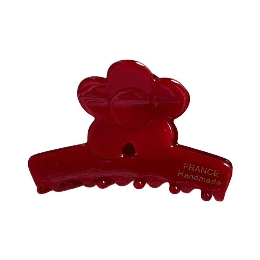 A close-up of a red flower-shaped claw clip with a glossy finish. Main image