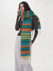 Woman wearing a long-sleeved dark top and light grey pants, with a colorful striped scarf draped around her neck.