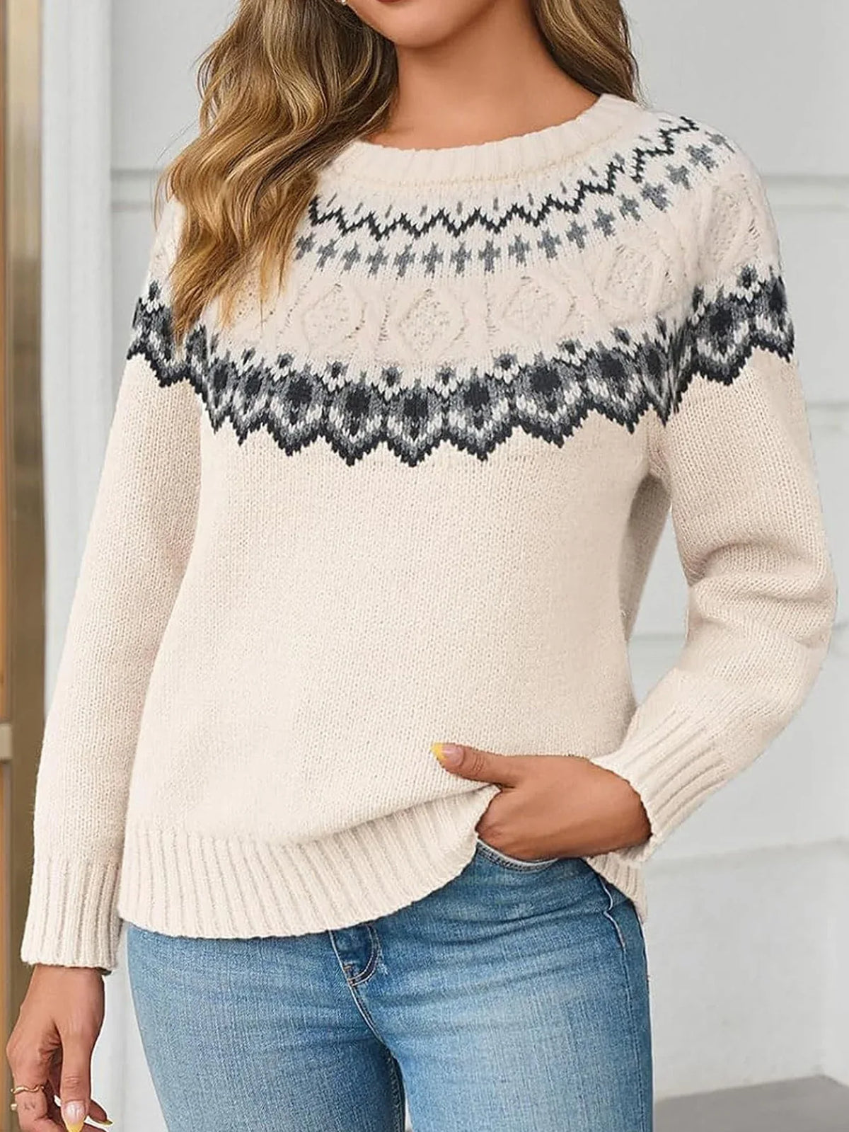 Woman wearing a cream-colored knit sweater with a Fair Isle pattern around the yoke and blue jeans.