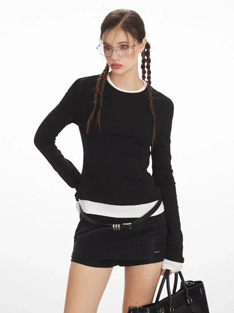 Close-up of a woman wearing a black long-sleeved top with white trim, black shorts, and glasses.