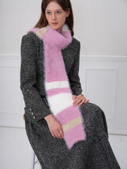 Woman sitting and wearing a pink, white, and beige striped fuzzy scarf.