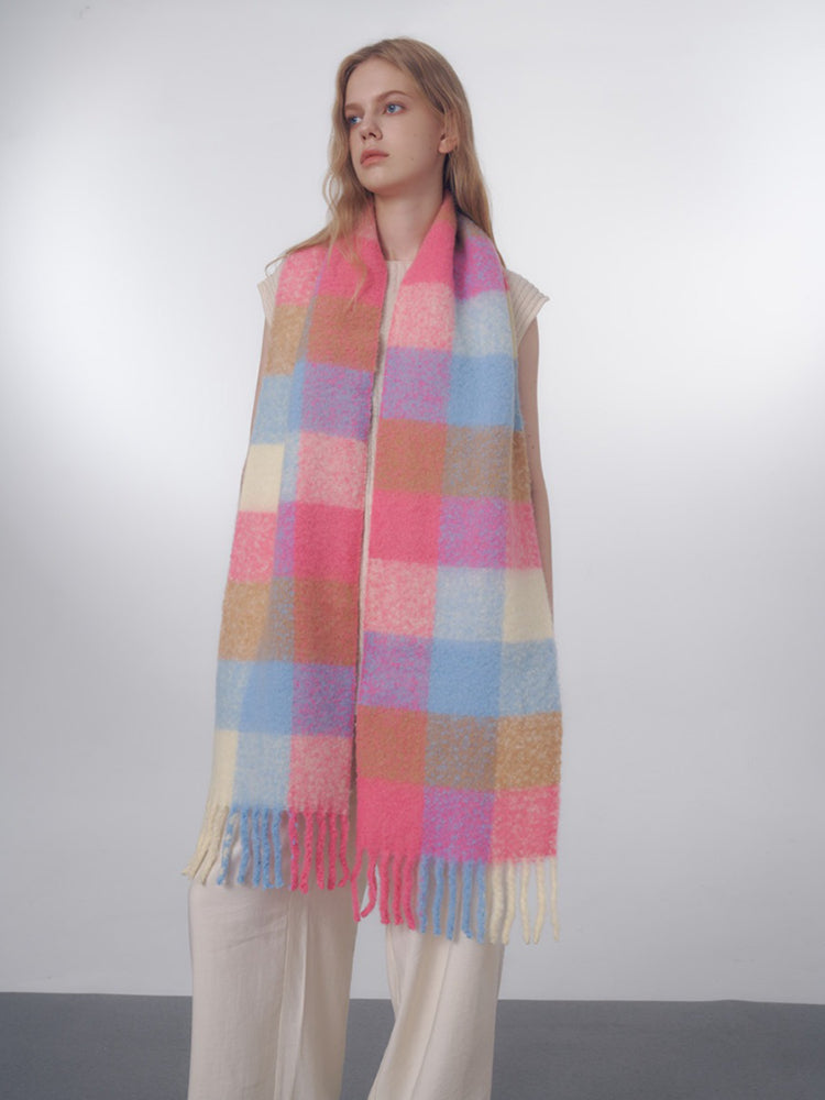 Close-up of the plaid pattern on the fuzzy knit scarf, showing the pink, blue, and tan colors and fringe.