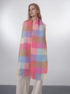 Close-up of the plaid pattern on the fuzzy knit scarf, showing the pink, blue, and tan colors and fringe.