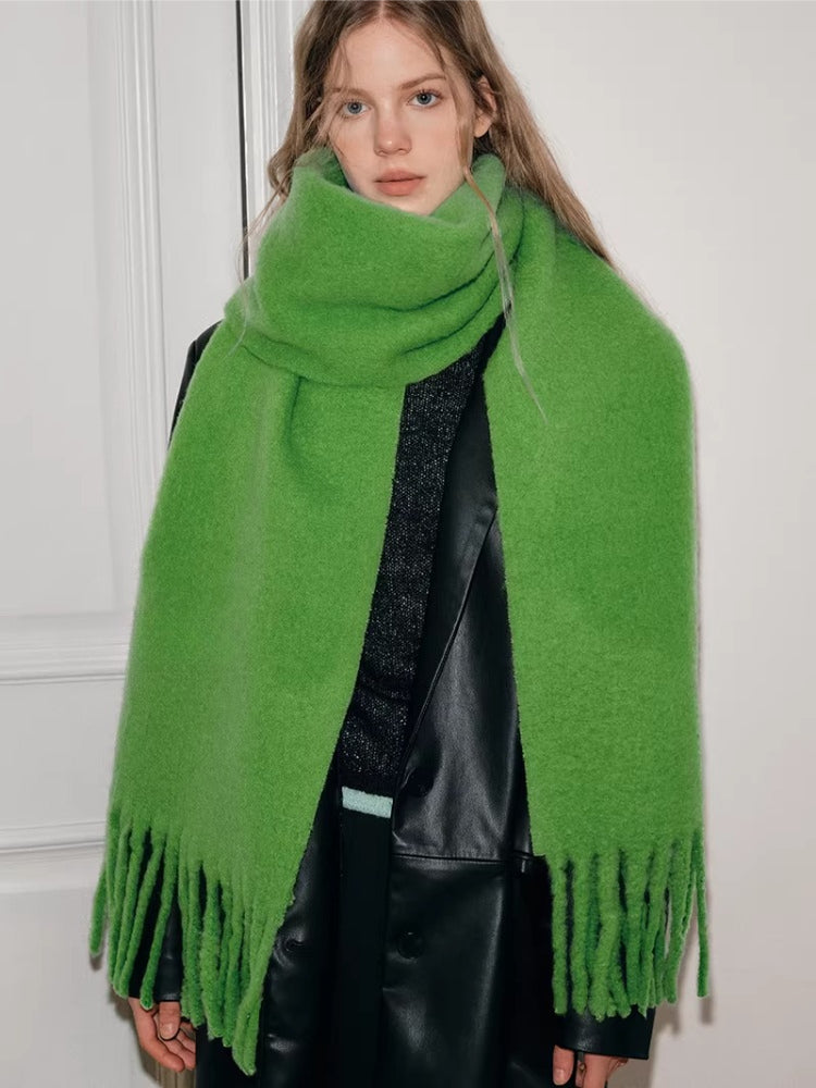 Woman wearing a bright green oversized scarf with fringed ends