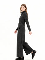 Model wearing a charcoal grey knit zip-up jacket and matching wide-leg pants, walking view.