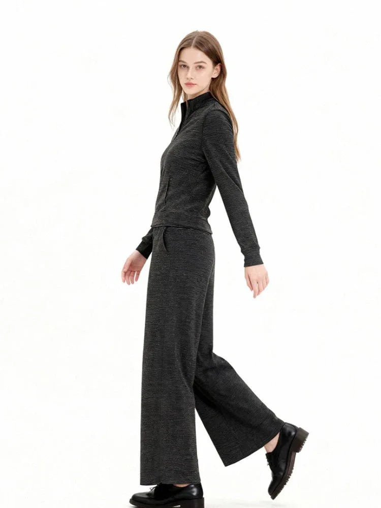 Model wearing a charcoal grey knit zip-up jacket and matching wide-leg pants, walking view.