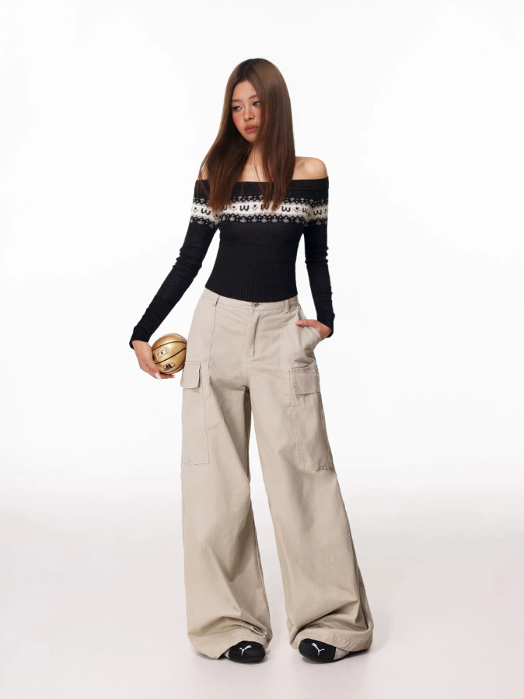 Full-body shot of a woman in a black off-the-shoulder knit top with a decorative yoke and loose-fitting beige cargo pants.